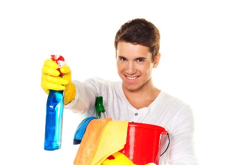 Technician treating upholstered chair with fabric cleaning equipment