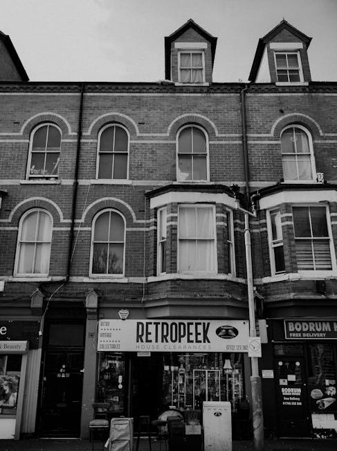 Exterior view of Edgware Cleaners' laundrette, a small white building with blue signage reading 'LAUNDERETTE' on both sides of the entrance. The entrance features a glass door with a blue frame and a 